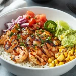 Grilled shrimp bowl with white rice, corn, guacamole, tomatoes, red onion, and jalapeño slices.