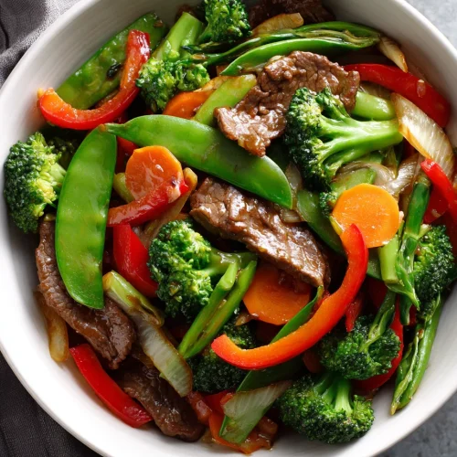 Beef and vegetable stir fry with broccoli, snap peas, carrots, onions, and red peppers in a savory sauce