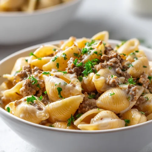 Creamy beef and shells pasta garnished with fresh parsley in a white bowl
