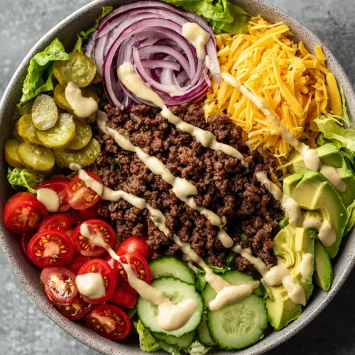 Burger bowl with seasoned ground beef, avocado, vegetables, and creamy dressing
