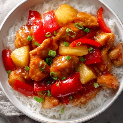 Crockpot sweet and sour chicken with pineapple chunks and red bell peppers over white rice