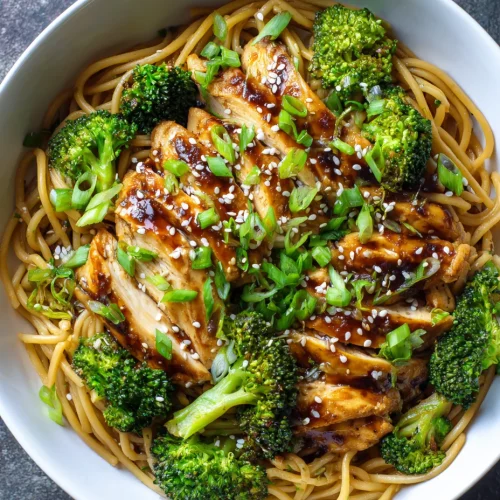 Spicy garlic chicken and broccoli noodle bowl topped with green onions