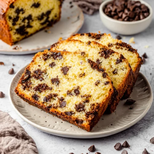 Slices of chocolate chip loaf cake on a plate with moist crumb and chocolate chips throughout.