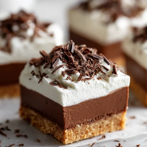 Chocolate cream pie bar with graham crust, smooth chocolate layer, whipped topping, and chocolate shavings.