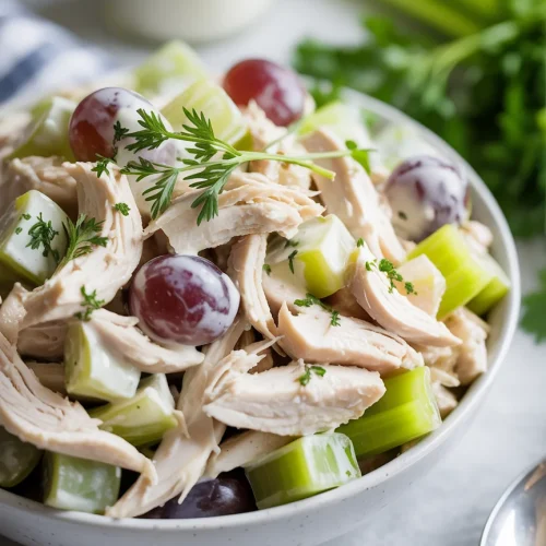 Classic chicken salad with shredded chicken, celery, grapes, and herb garnish
