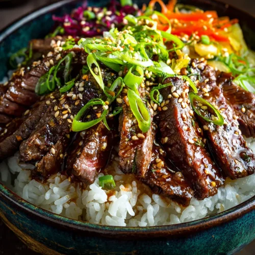 Korean steak rice bowl with glazed beef slices, white rice, sesame seeds, scallions, and pickled vegetables.