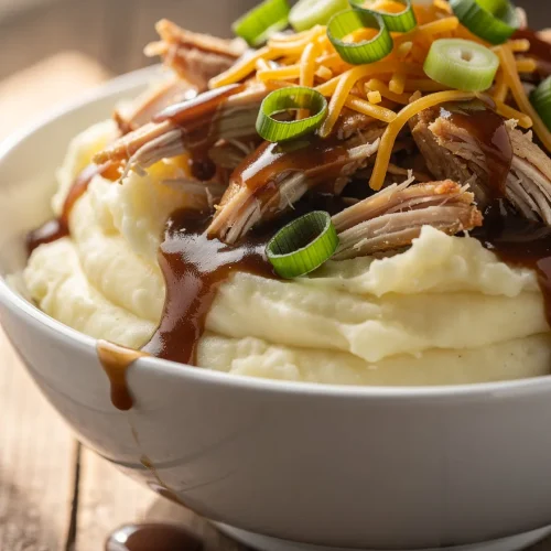 Loaded chicken and gravy mashed potato bowl with shredded chicken, cheddar cheese, and green onions