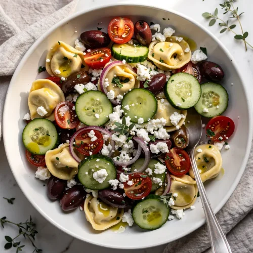 Greek tortellini salad recipe with feta, cucumbers, olives, cherry tomatoes, and red onion