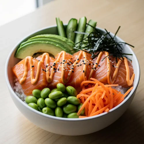 Salmon sushi bowl with avocado, cucumber, edamame, carrots, seaweed, and spicy mayo over rice.
